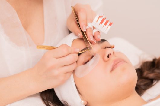A skillful cosmetologist doing lash extension procedure - Beauty concept