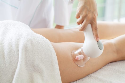 Woman getting LPG massage for skin care in home.
